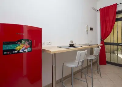 a kitchen with a red refrigerator and a counter with stools at Il Cortiletto di Via Tuscolana in Rome