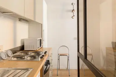 a kitchen with a sink and a counter with chairs at A World Aparts - 13 T.Argentina in Rome