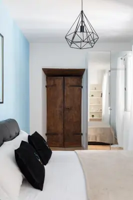 a bed with black and white pillows and a blue wall at A World Aparts - 13 T.Argentina in Rome