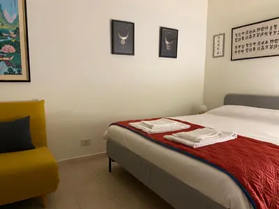 a bedroom with a bed and a yellow chair at Suite China Soul - Flaminio - Olimpico - Auditorium in Rome