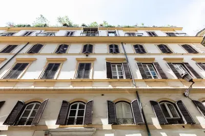 a tall white building with windows and shutters at Louly Trevi Fountain in Rome