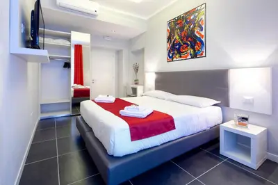 a bedroom with a large bed with a red blanket at NearHome Smart Suites Guest House in Rome