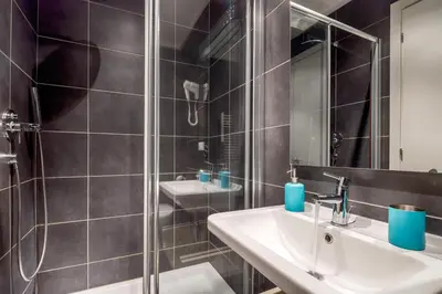a bathroom with two sinks and a glass shower at NearHome Smart Suites Guest House in Rome