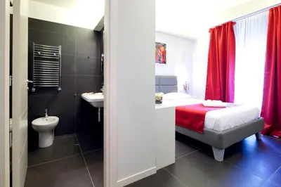 a bathroom with a bed and a sink and a toilet at NearHome Smart Suites Guest House in Rome