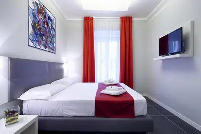 a bedroom with a bed with red curtains and a tv at NearHome Smart Suites Guest House in Rome