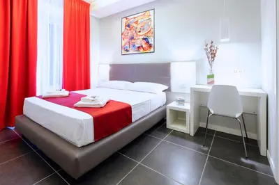 a bedroom with a bed with red curtains and a chair at NearHome Smart Suites Guest House in Rome
