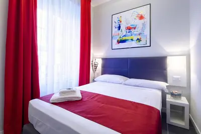 a bedroom with a large bed with red curtains at NearHome Smart Suites Guest House in Rome