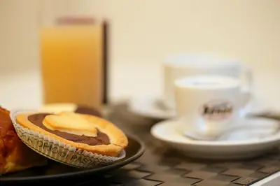 a plate with a piece of bread and a cup of coffee at NearHome Smart Suites Guest House in Rome