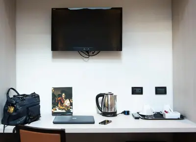 a desk with a monitor and a laptop and a bag at Borgo Pio Suites Inn in Rome