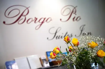 a vase of flowers on a table with a sign on the wall at Borgo Pio Suites Inn in Rome