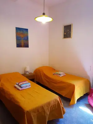 two beds in a room with orange sheets at old corallo in Rome