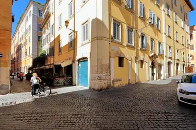 a woman walking a bike down a street with buildings at Campo Dei Fiori Home in Rome
