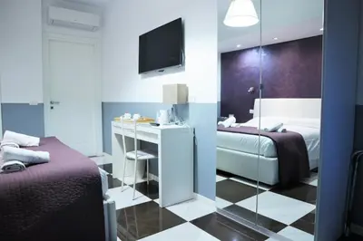 a hotel room with two beds and a desk at Luxury Vatican Rooms in Rome