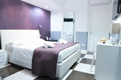 a bedroom with a white bed and a purple wall at Luxury Vatican Rooms in Rome