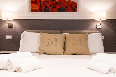 a bedroom with a white bed with pillows and a painting at La Maison di Sant'Anna in Rome