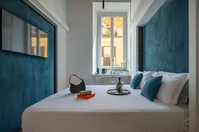 a large white bed with a tray of books on it at Hadrianus Temple Suites - The Venue Collection in Rome