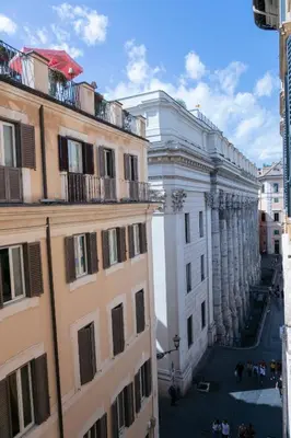 a view of a white building from between two buildings at Hadrianus Temple Suites - The Venue Collection in Rome