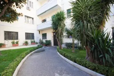 a street in front of a white building with palm trees at Easylife in Rome