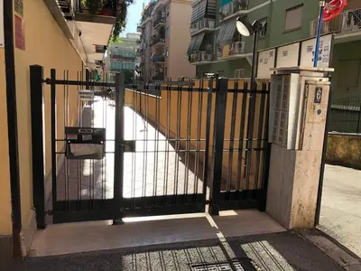 an iron gate with a sidewalk in front of a building at The Royals in Rome