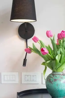 a lamp and a vase with pink flowers in it at AventinoHome in Rome