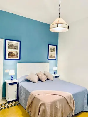 a bedroom with blue walls and a bed with two tables at Mama Roma Domus in Rome