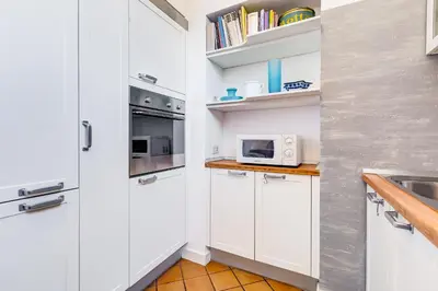a kitchen with white cabinets and a sink and a microwave at Colosseum Terrace Apartment in Rome