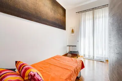 a bedroom with an orange bed and a large window at Colosseum Terrace Apartment in Rome