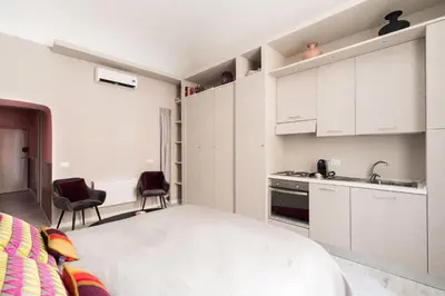 a kitchen with white cabinets and a bed in a room at Apt.Prati L.T. (Vatican and center) in Rome