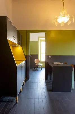a kitchen with green walls and a table and a chandelier at MODO Rooms & Suite Rome in Rome