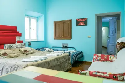 a blue room with two beds and a chair at Signor Suite Colosseo in Rome