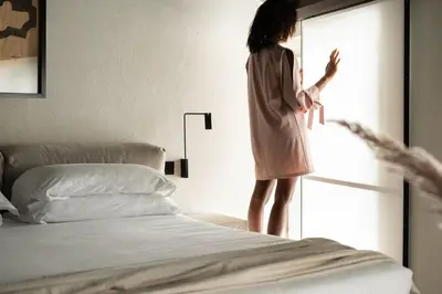 a woman standing next to a bed looking out the window at Hotel Scenario in Rome
