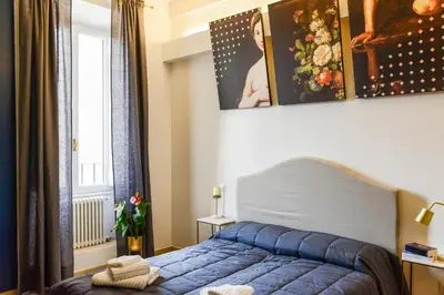 a bedroom with a blue bed and a window at San Pietro Suite Rome in Rome
