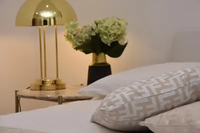 a vase of flowers on a table next to a bed at Diasof Apartments in Rome