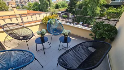 a balcony with three chairs and a table with flowers at Diasof Apartments in Rome