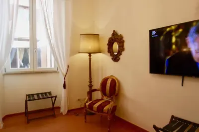 a living room with a lamp and a chair and a tv at Visione Via Sant’Andrea delle Fratte, 36 in Rome