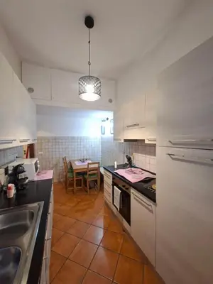 a kitchen with white cabinets and a table in it at Athena's Apartment in Rome