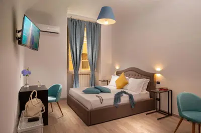 a bedroom with a bed with blue chairs and a television at The Shell Rome Suite in Rome
