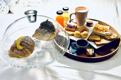 a table with a tray of pastries and a plate of food at Rooftop Colosseo - Roma d'Amore in Rome