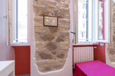 a room with a stone wall and a pink ottoman at Museum Inn - Una finestra sui Musei Vaticani in Rome