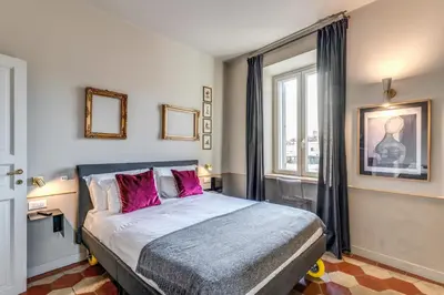 a bedroom with a bed with pink pillows and a window at CORNER211 in Rome