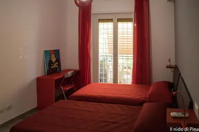 a bedroom with two beds and a window with red curtains at Nido di Pina in Rome