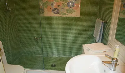 a green tiled bathroom with a sink and a shower at Montebello - Julia Apartment in Rome