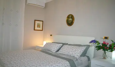 a white bedroom with a bed and a vase of flowers at Montebello - Julia Apartment in Rome