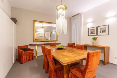 a dining room with a wooden table and orange chairs at Spanish Steps DeLuxe Apartment in Rome