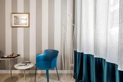 a room with a blue chair and a shower curtain at La Finestra su Fontana di Trevi - Charming View in Rome