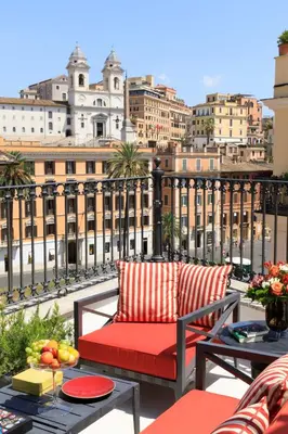 a balcony with a red couch and a view of the city at Rocco Forte House Piazza Di Spagna, Rome in Rome