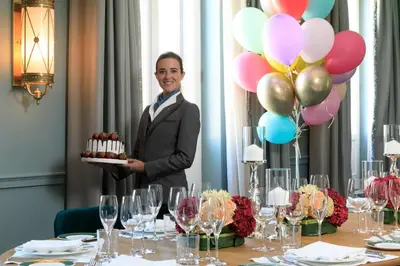 a man is holding a table with a cake and balloons at Rocco Forte House Piazza Di Spagna, Rome in Rome