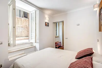 a white bedroom with a bed and two windows at Novembre 152 Apartment in Rome