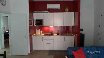 a kitchen with white cabinets and a red wall at Casa di Rosita in Rome