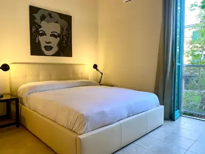 a bedroom with a white bed with a painting on the wall at Suite Marilyn - Flaminio - Olimpico - Auditorium in Rome
